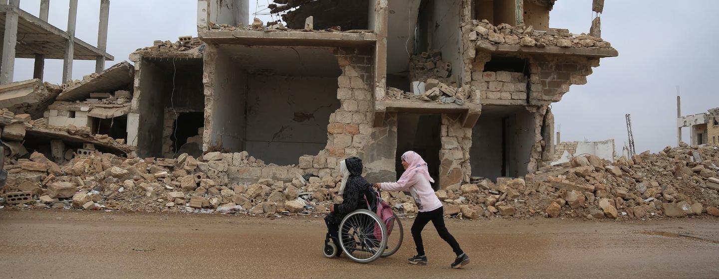 A girl helps her sister on their way home from school in Idlib, Syria.